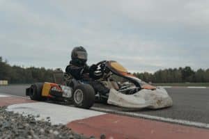 Un pilote de kart en tenue complète naviguant sur une piste de course lors d'une compétition.