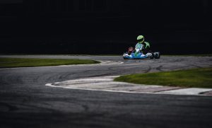 Dynamic photo of a go-kart racer speeding through a track's curve, showcasing the thrill of motorsport.